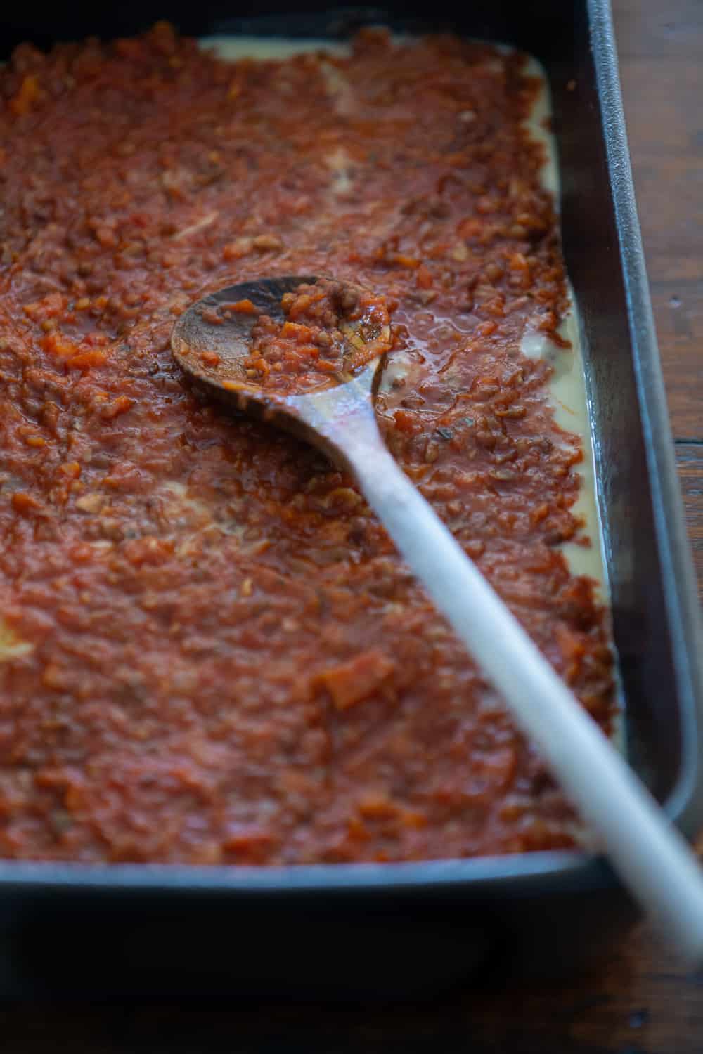 Layering of lentil sauce in baking dish