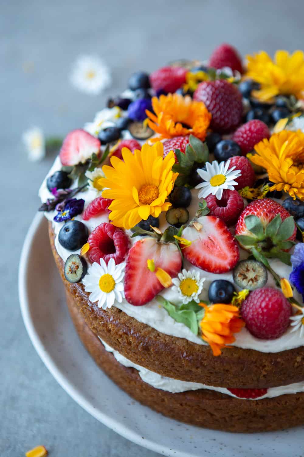Close up of cake with berries and edible flowers.