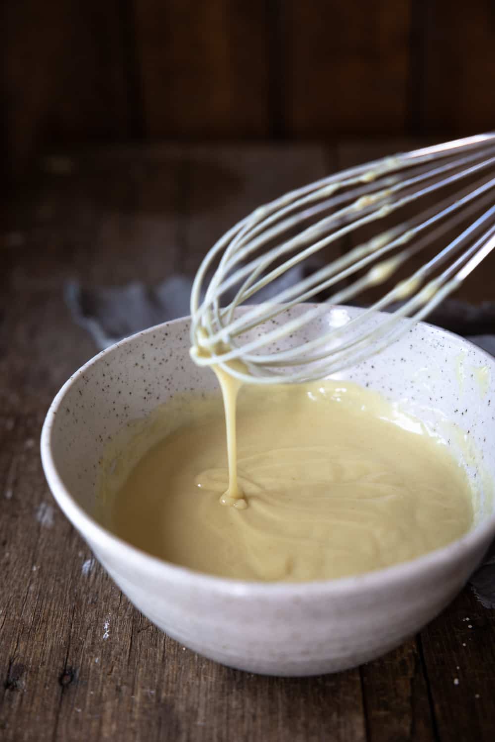 Thicker custard in bowl with whisk.