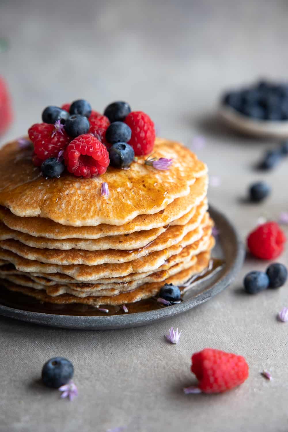 Close up of pancake stack with berries and maple syrup.