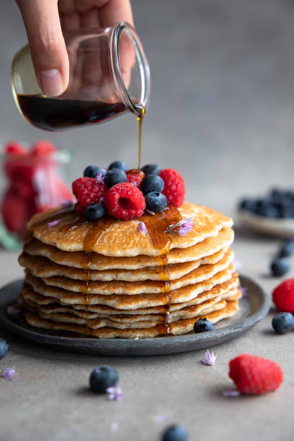Drizzling maple syrup over the stack of pancakes.
