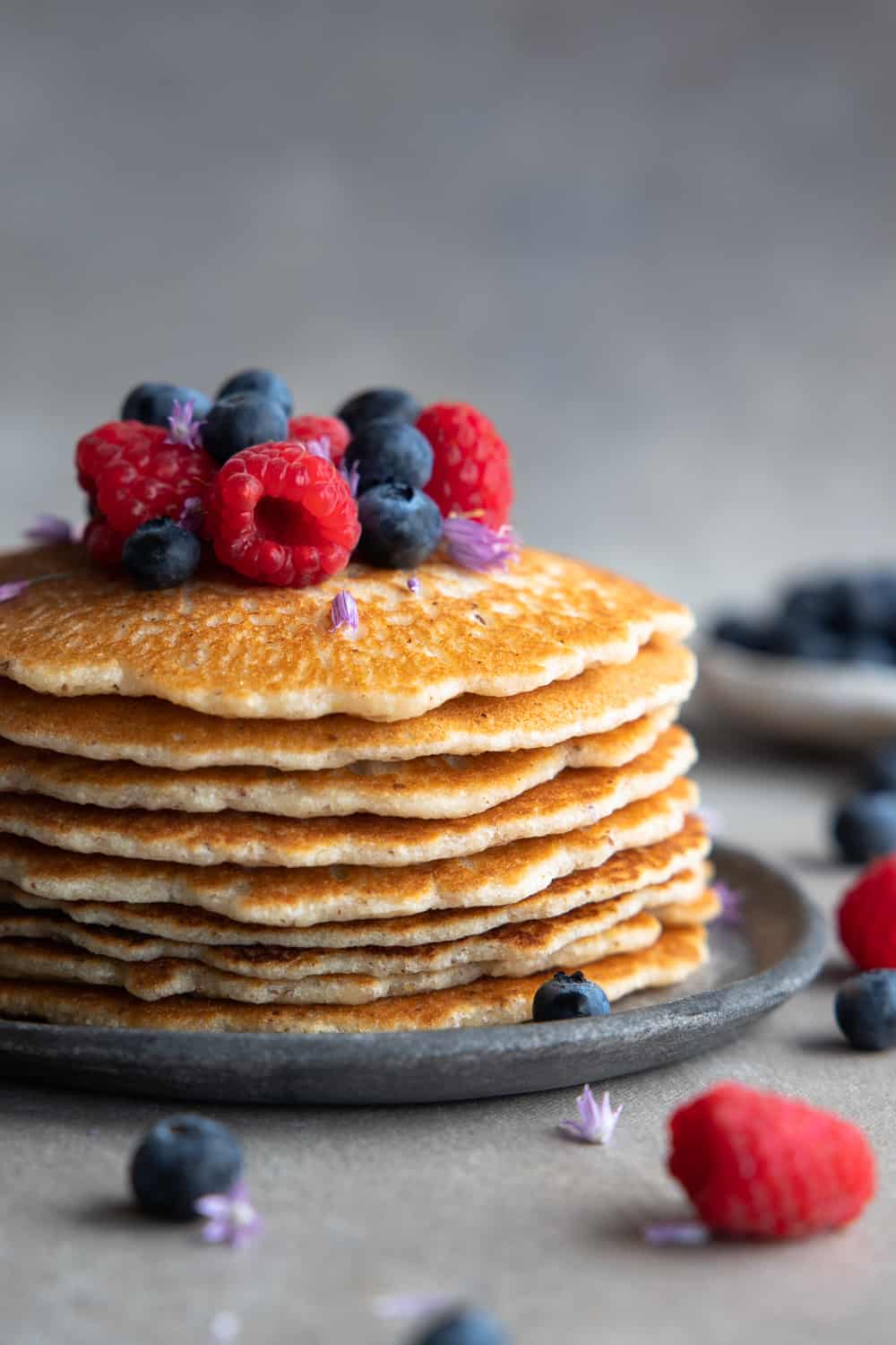Close up for vegan paleo pancakes stacked with berries on top.