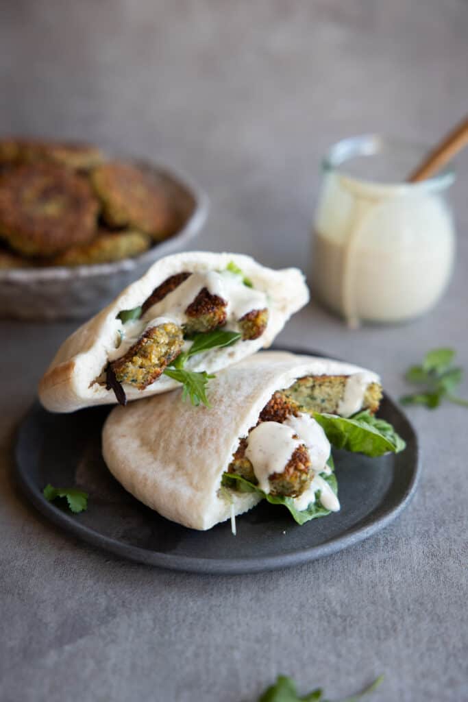 Falafel pockets stacked on top of each other with tahini sauce.