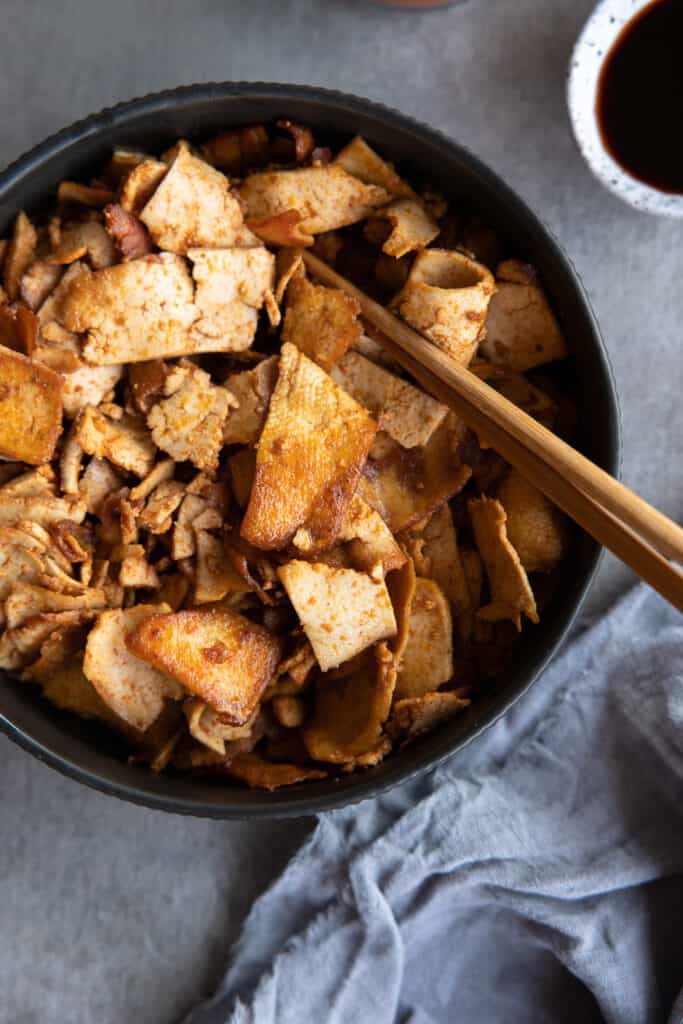 Crispy tofu in a bowl with chopsticks.