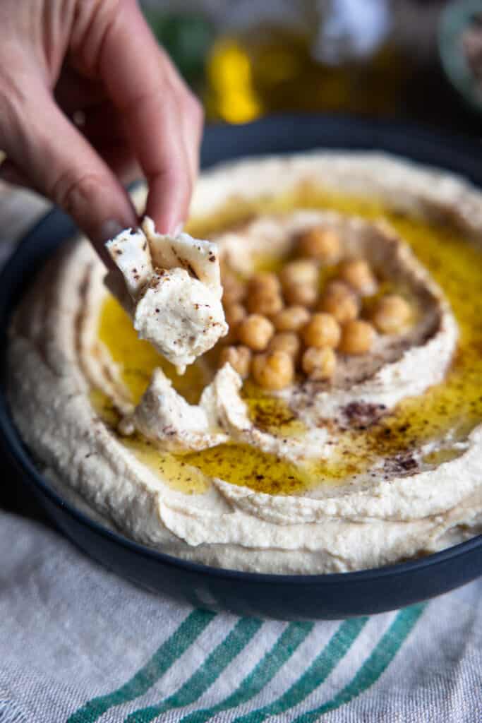 Hummus being scooped out with some bread.