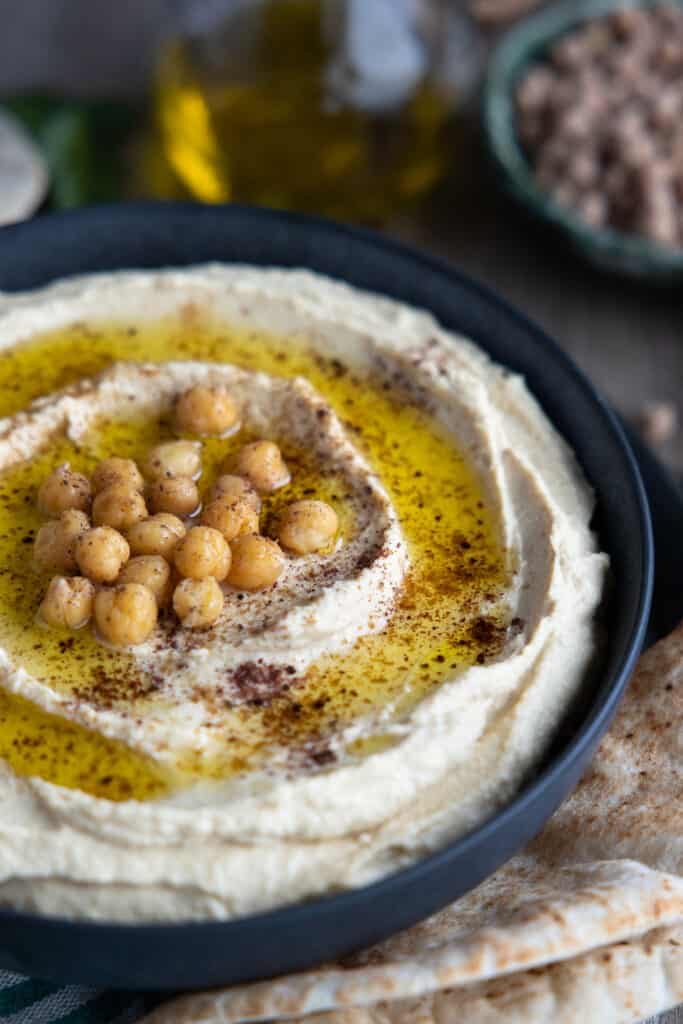 Hummus close up with olive oil and freshly cooked chickpeas on top.