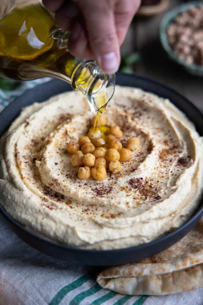 Drizzling olive oil over homemade hummus.