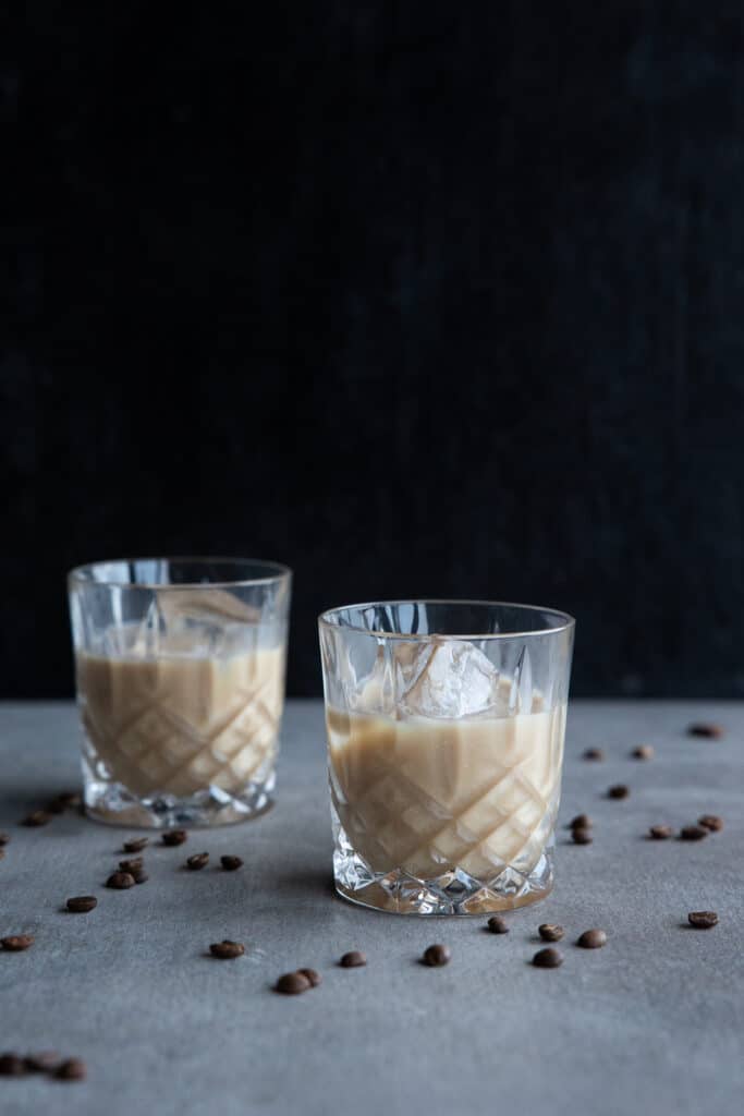 Vegan White Russian Cocktails in two glasses with large ice cubes.