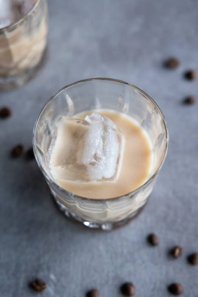 Close up on an angle overhead of the white Russian cocktail in a glass with ice cubes.