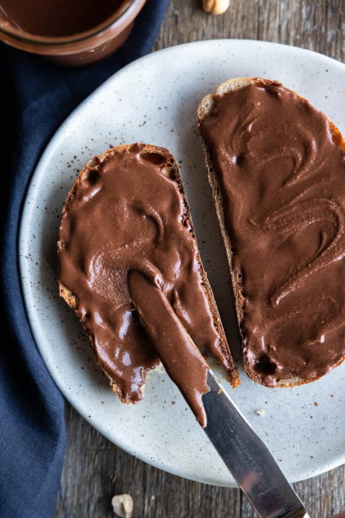 Chocolate hazelnut spread is spread onto toast.