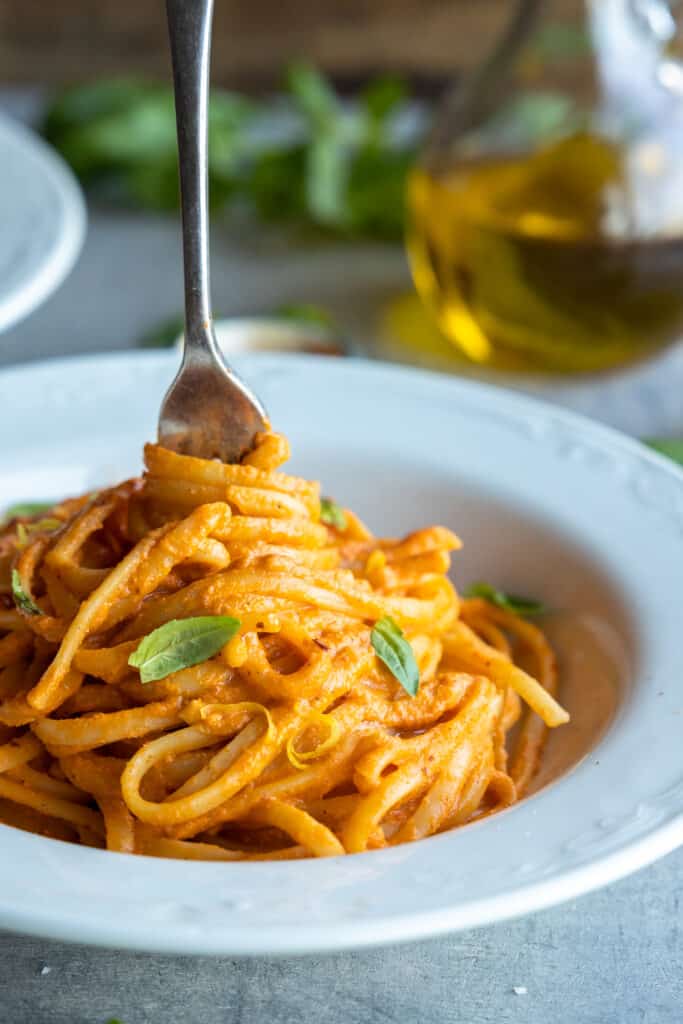Close up of vegan red pepper pasta on fork twirled on a plate. 