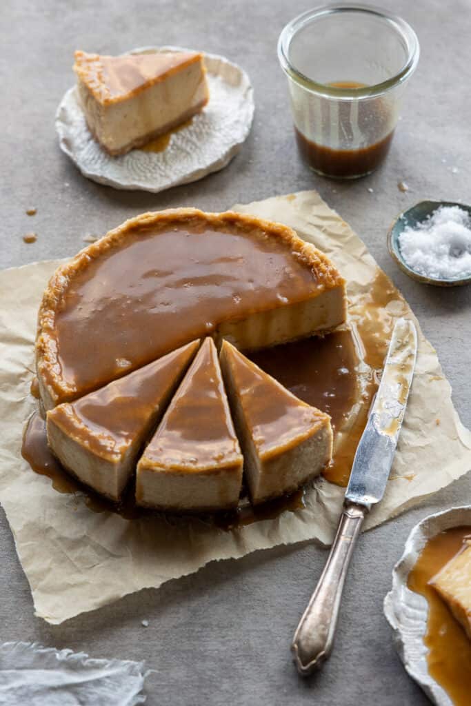 Full salted caramel cheesecake with slices cut. 
