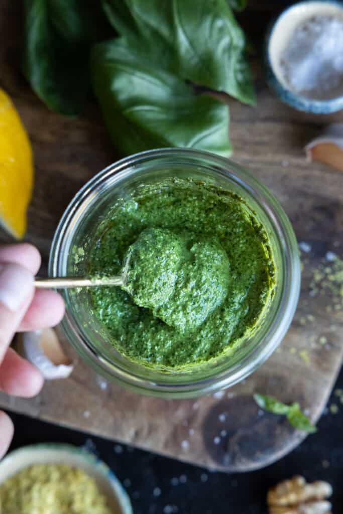 Scooping out walnut pesto from a jar.