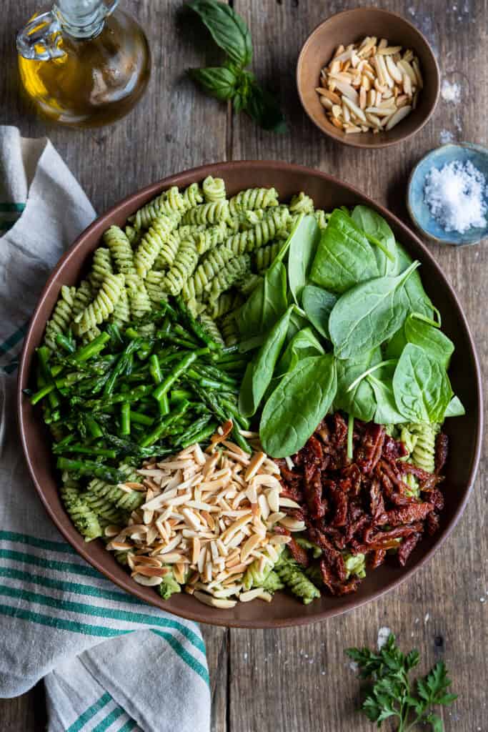 Ingredients are placed on top of the pesto pasta.