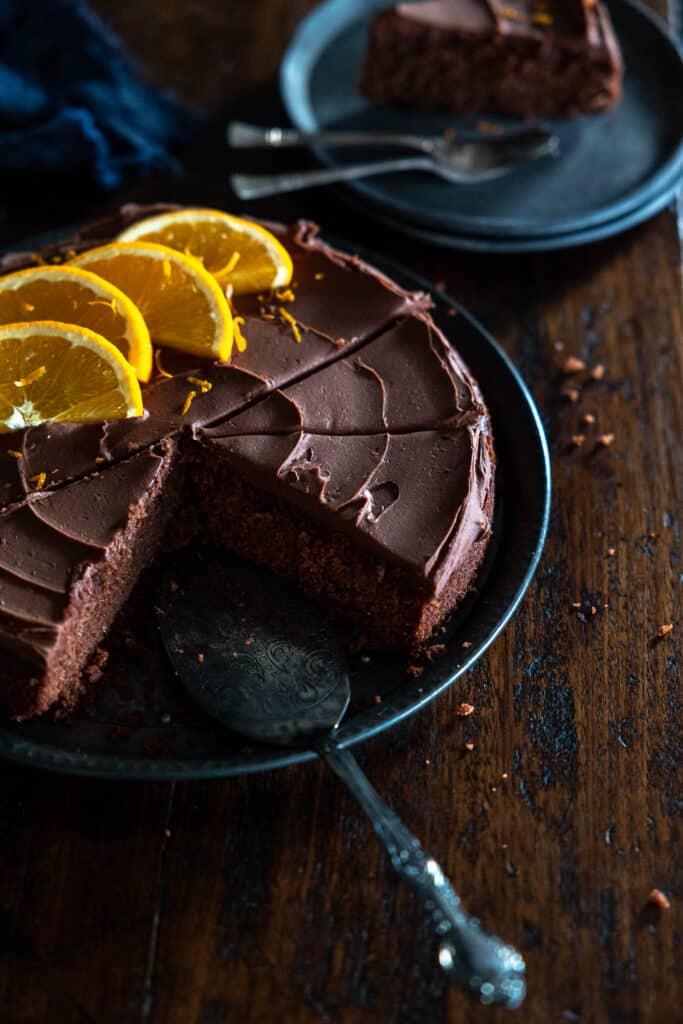 Slices removed from a whole vegan chocolate orange cake.