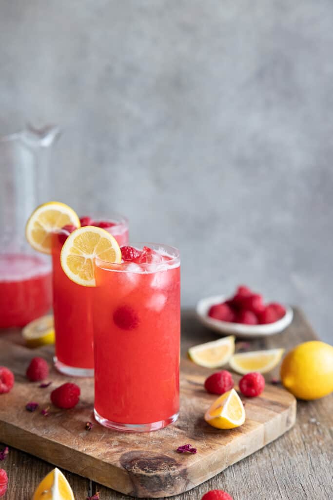Raspberry lemonade in glasses on a chopping board.