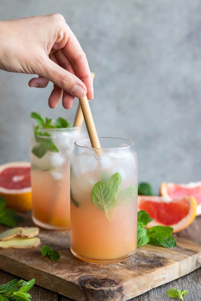 Stirring the grapefruit ginger spritzer with a bamboo straw.