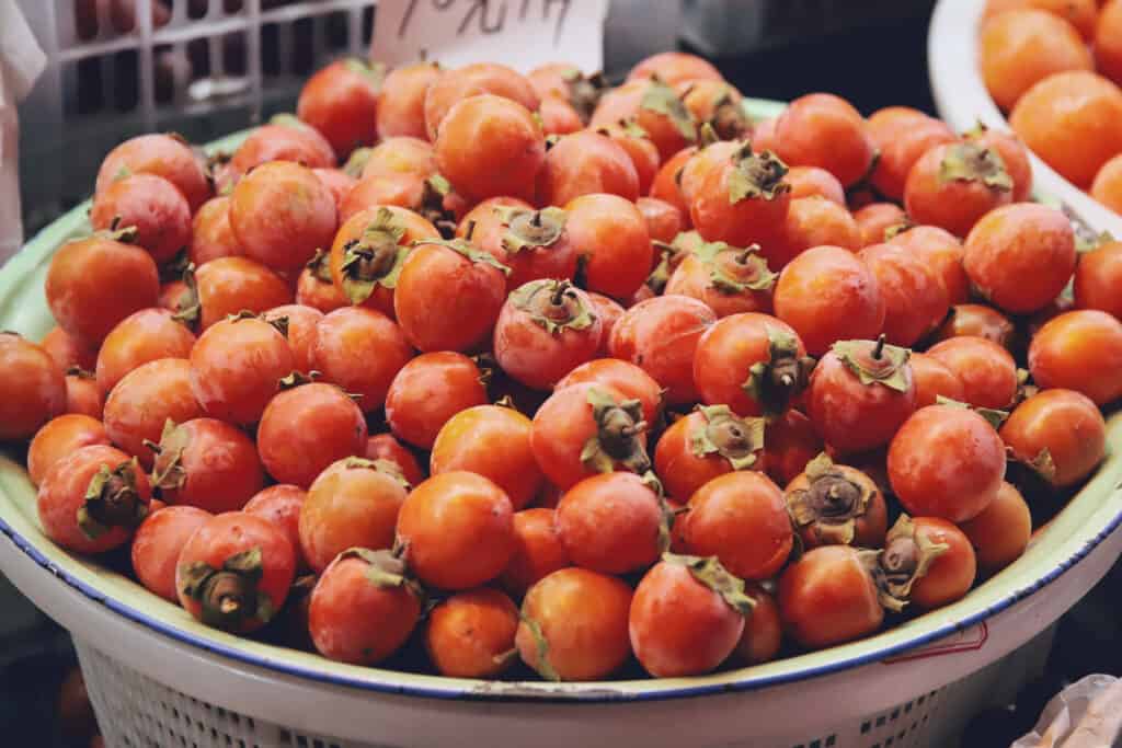Astringent persimmons in a bowl at a market.