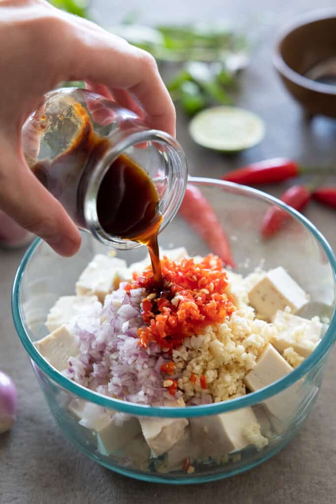 Pouring liquid marinade into the rest of the lemongrass tofu mix. 