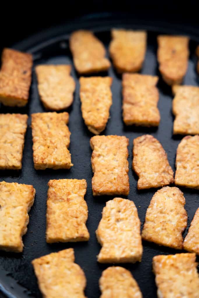 Frying slices of tempeh.
