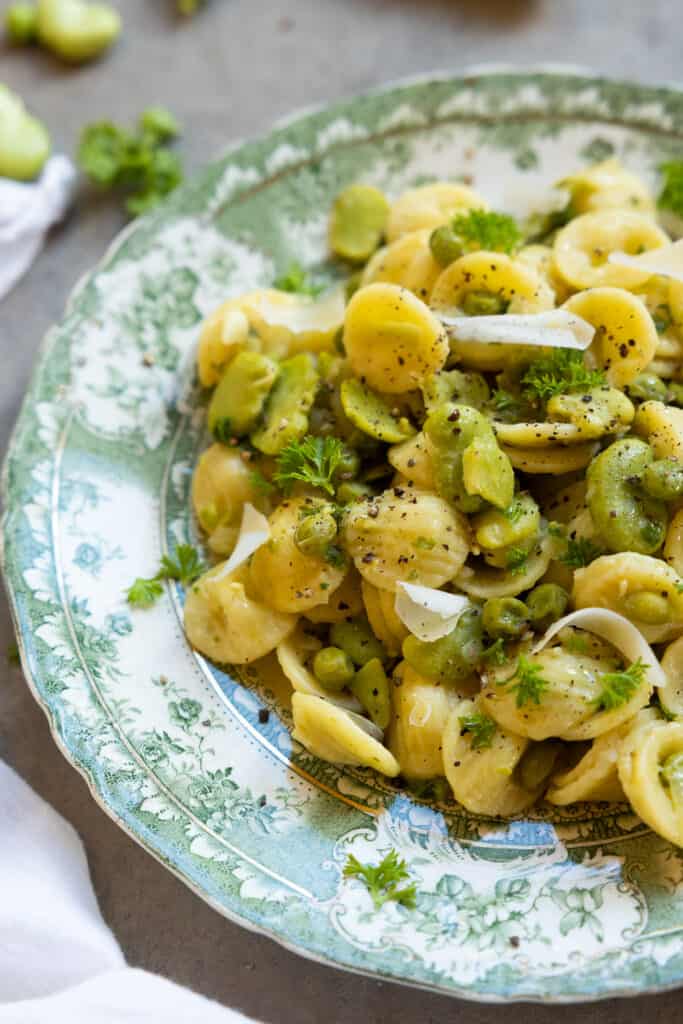 Close up of broad bean pasta on a green plate.