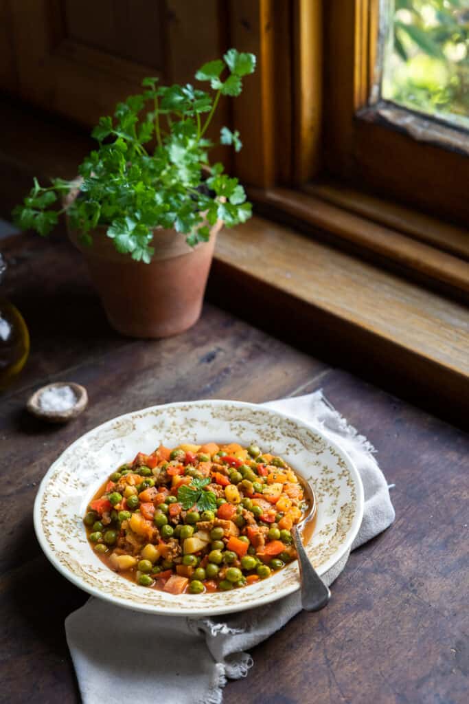 Turkish pea stew served in a soup plate near a window. 